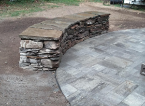 Stone sitting wall for a backyard patio by DeJohn Landscaping